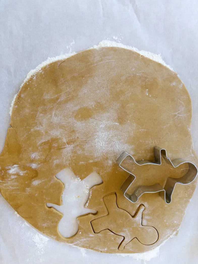 cutting out the cookies with the gingerbread man cookie cutter