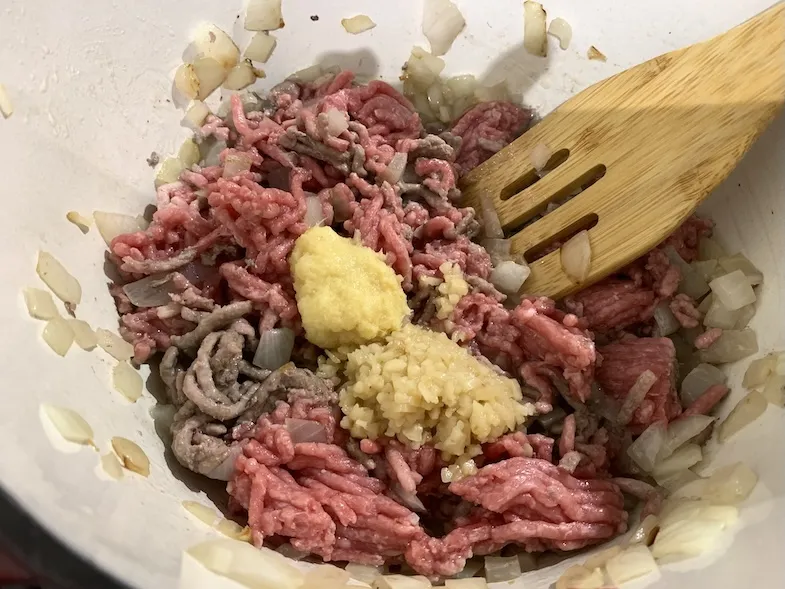 adding ground meat and ginger to the onion mixture